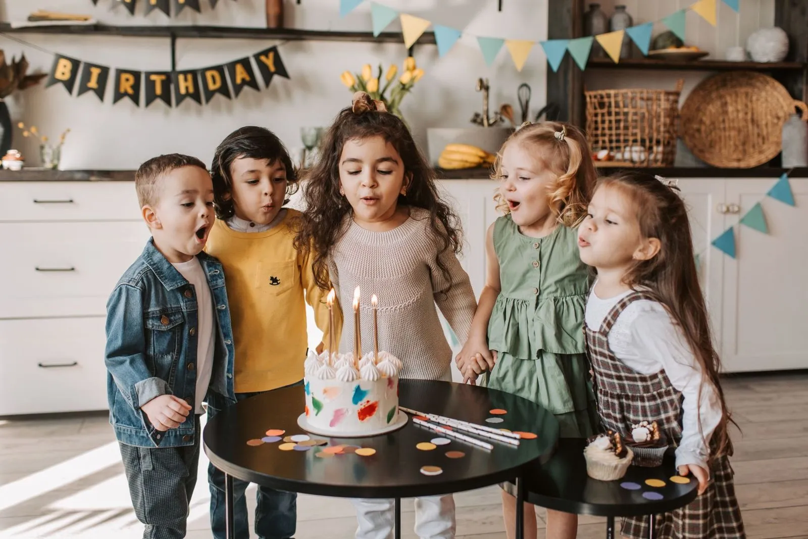 Kinder pusten auf einer Geburtstagsfeier gemeinsam die Kerzen auf der Torte aus